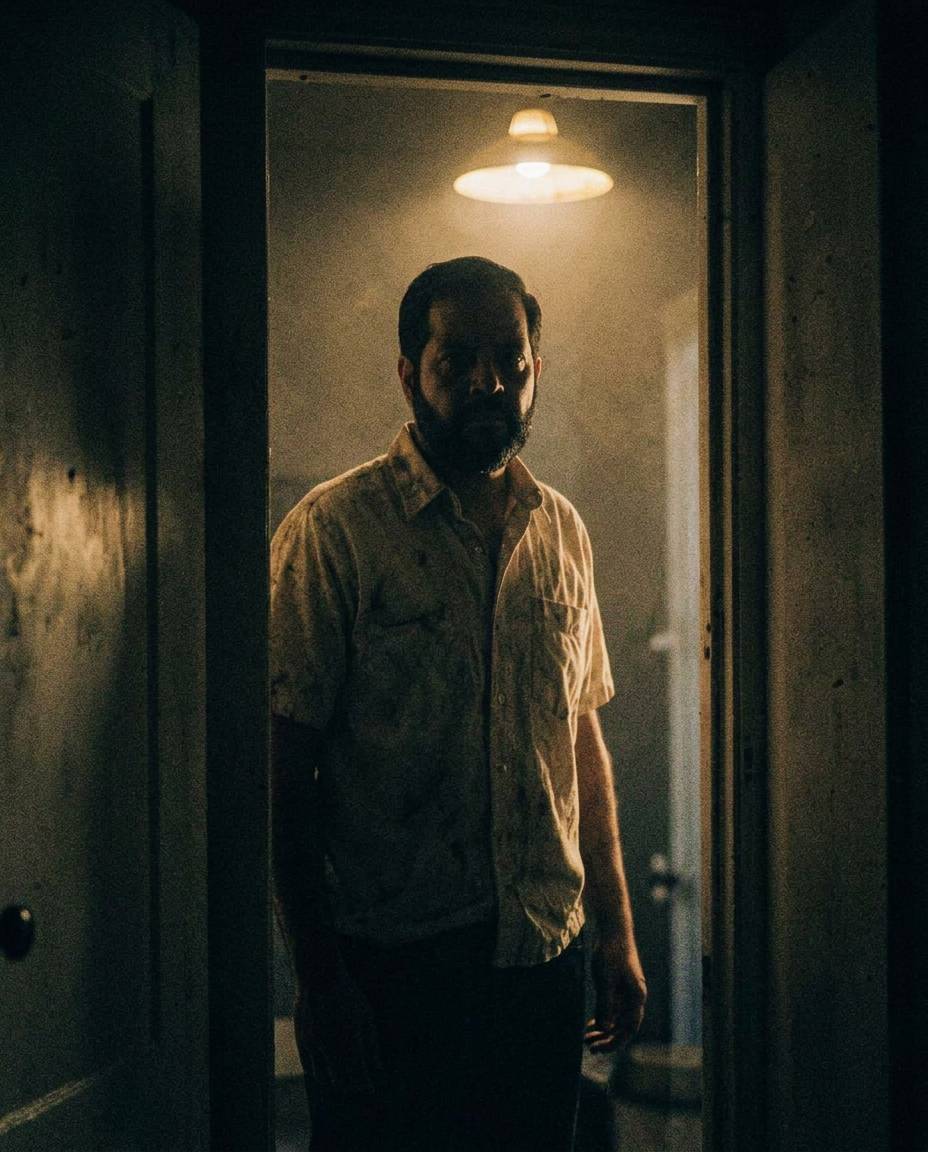 A man standing in a dark doorway under a single lamp